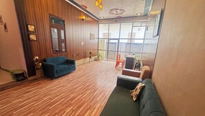 Un hall d’entrée spacieux avec un plancher en bois, un canapé bleu et un canapé vert.