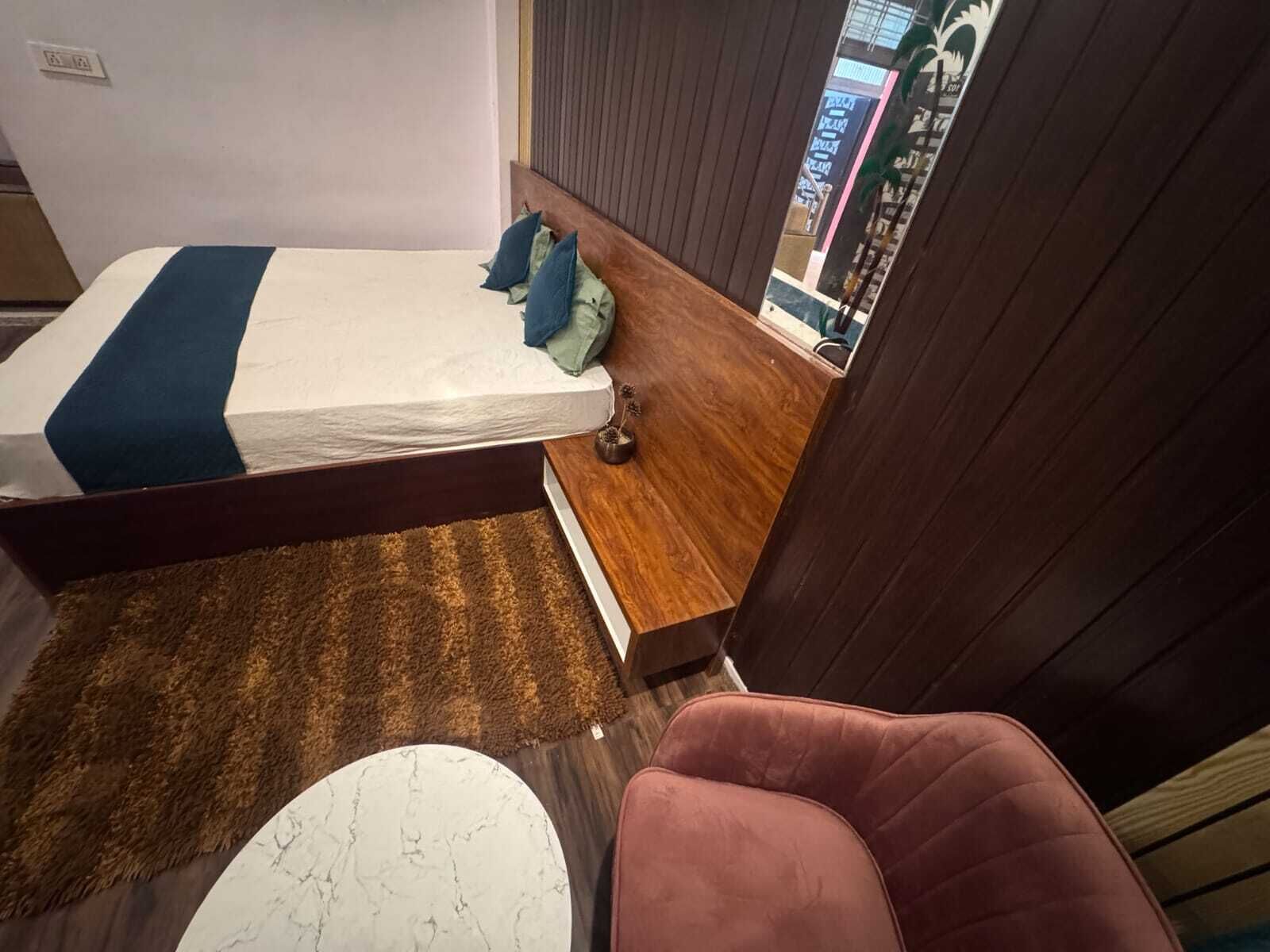 Une chambre à coucher avec un lit, une petite table en bois, une chaise et une vue sur l’extérieur.