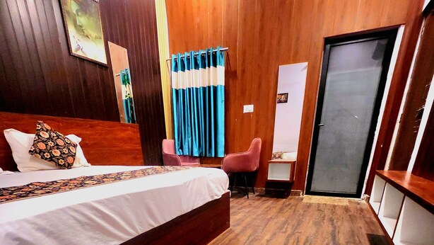 Une chambre d’hôtel avec un plancher en bois, un lit agrémenté d’un coussin à motifs floraux, un bureau avec une chaise et une porte.