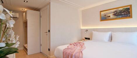 A hotel room with a bed, a painting on the wall, and a door leading to another room.