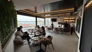 Un espace de restauration moderne avec vue sur la ville, comprenant un bar et différents types de sièges.