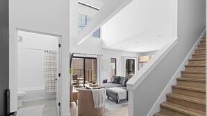 A spacious living area with a staircase, a sofa, and a coffee table. - Luxury Penthouse w/ 2 Floors - Pool, Patio, Gym, Walk to Broadway (Nashville)
