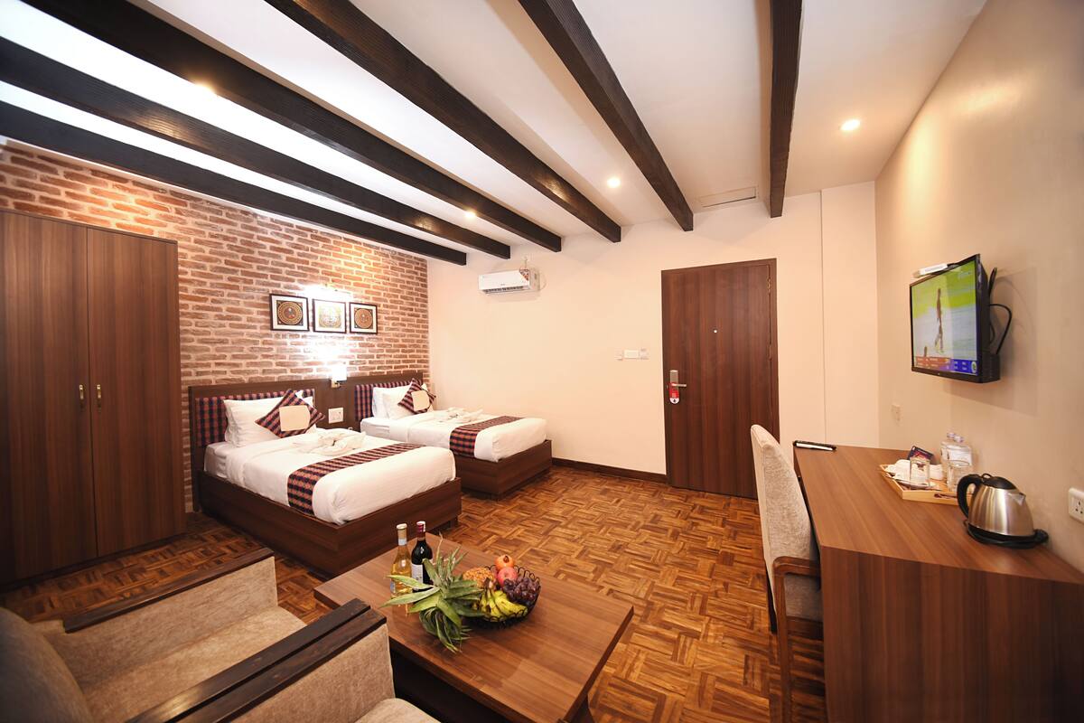 Habitación de hotel con pared de ladrillo, muebles de madera, cama, escritorio y televisor.