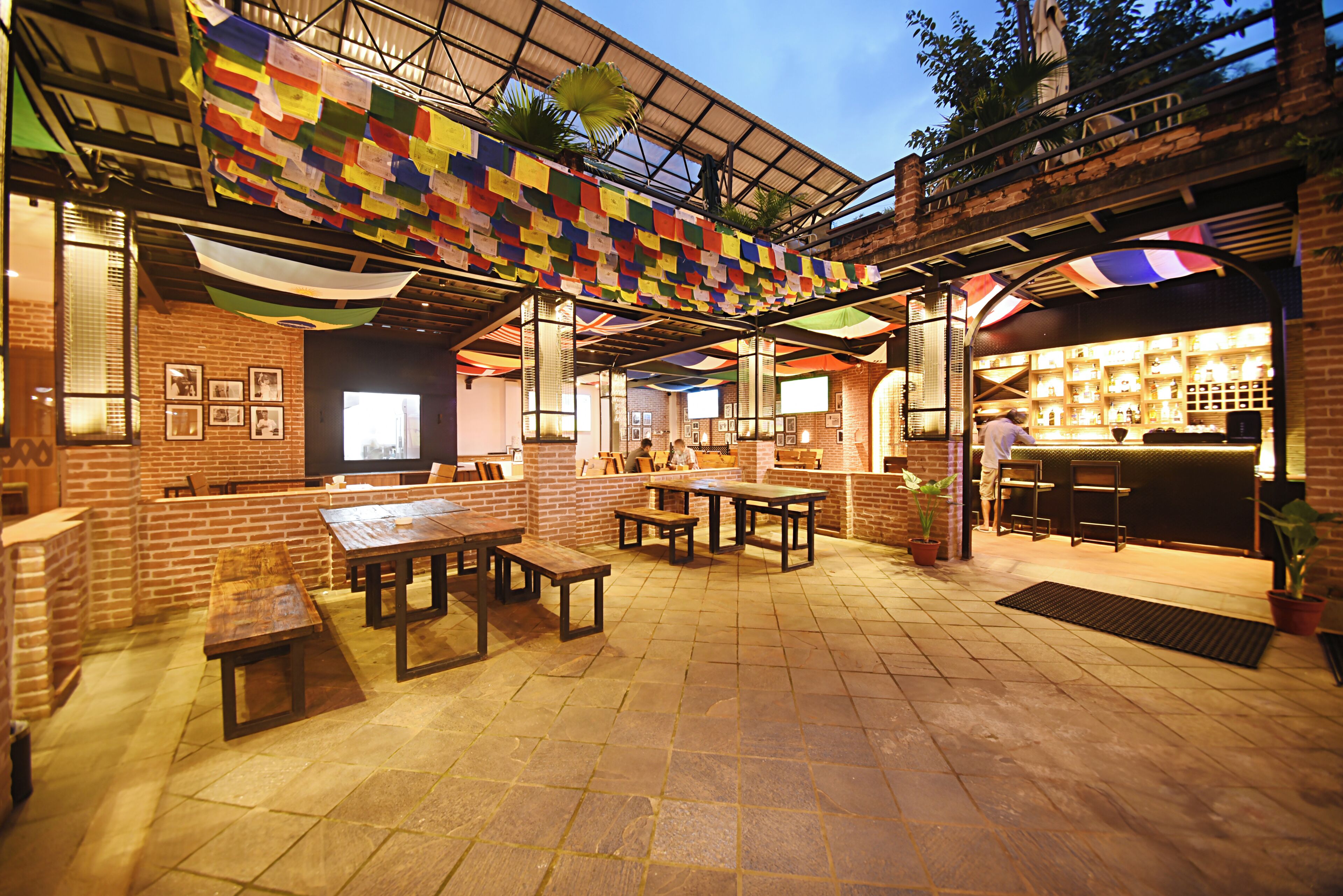 An outdoor patio area with brick walls, wooden tables, and benches.