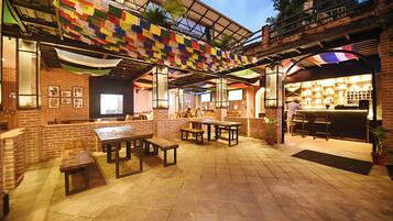 Un patio al aire libre con muros de ladrillo, mesas y bancos de madera.
