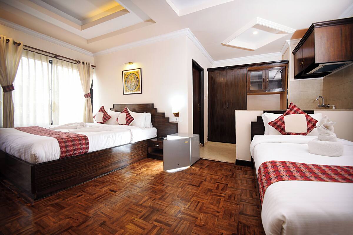 Una habitación de hotel con dos camas, un escritorio pequeño, un armario y una kitchenette.