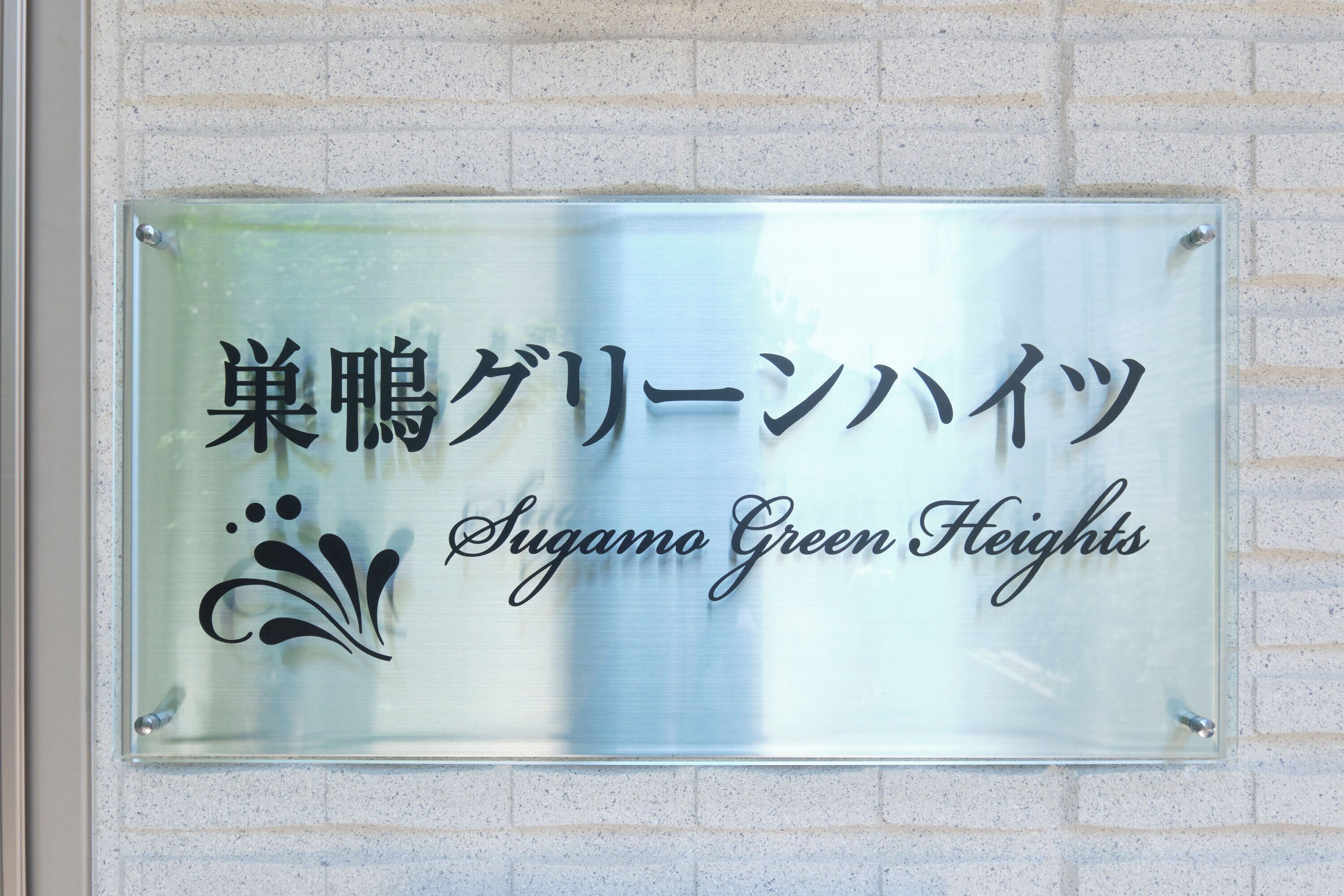Une enseigne avec des caractères japonais et le texte en anglais : « Sugamo Green Heights ».