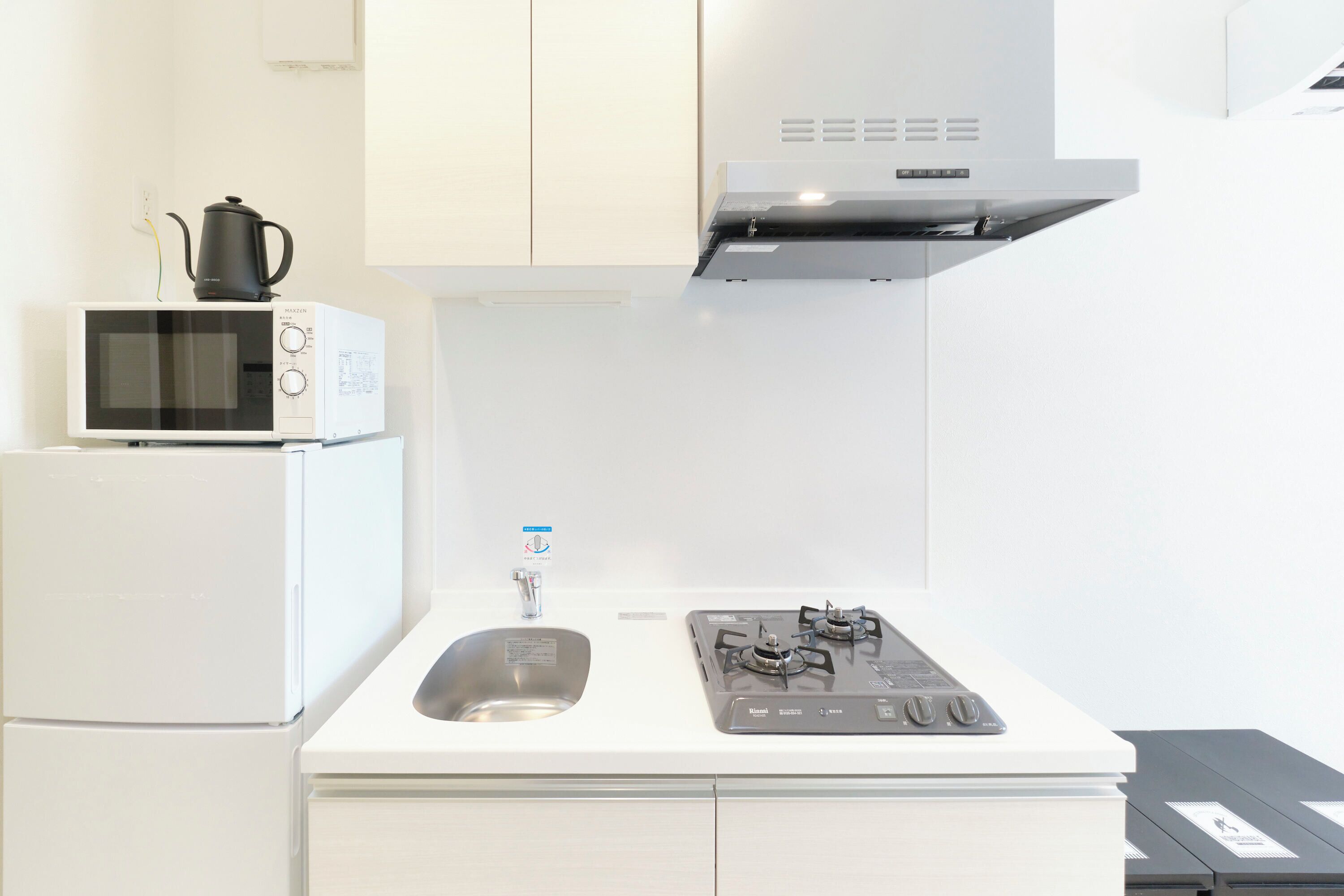 Une cuisine compacte équipée d’un four à micro-ondes, d’un évier et d’une cuisinière à gaz.