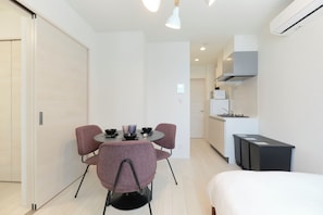 Habitació d'hotel moderna amb zona de menjador, cuina sencera i un llit.