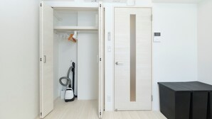 A room with a closet, a vacuum cleaner, and a black table.