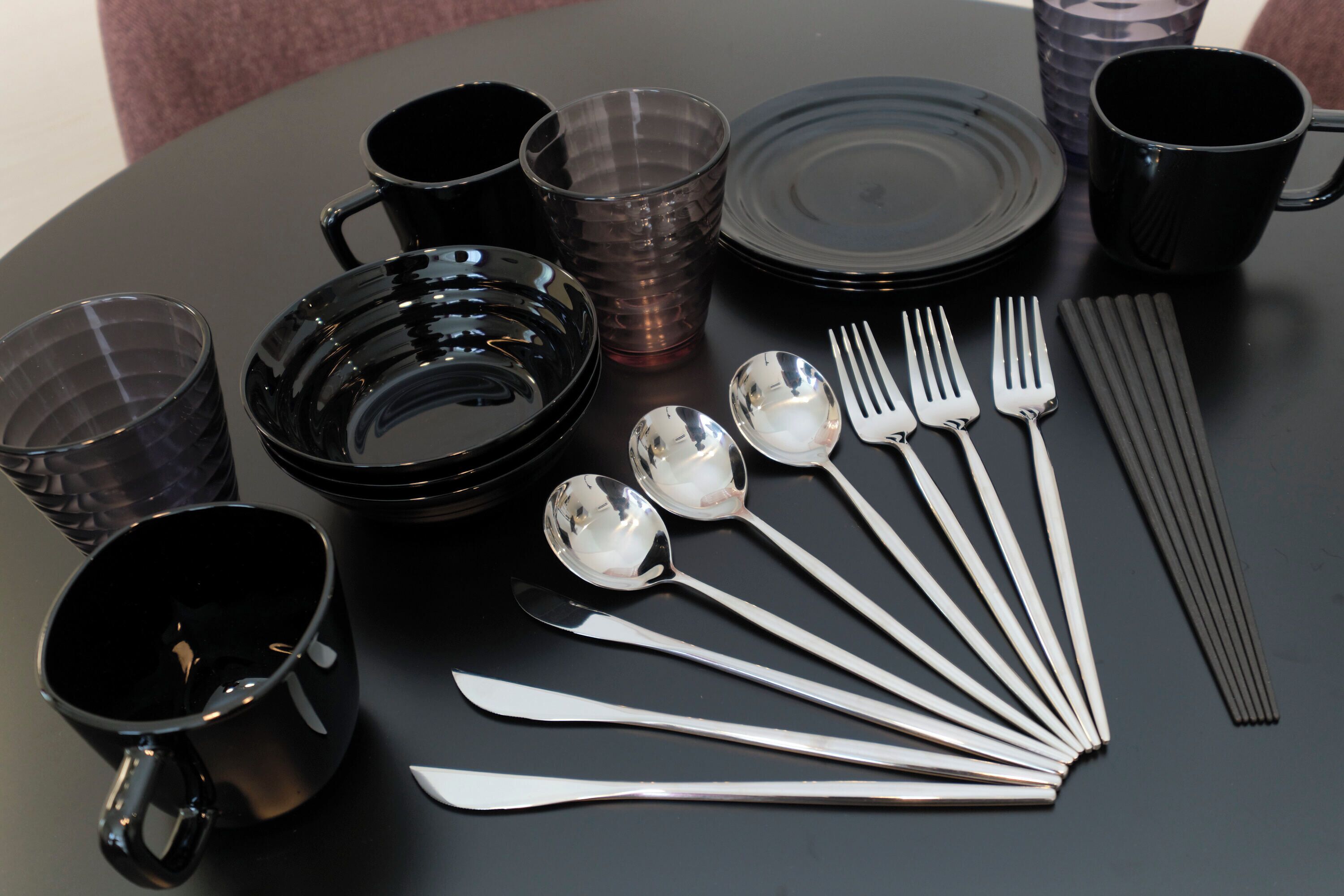 A table set with black and clear glassware, silverware, and plates.