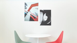 A white table with two modern chairs, one green and one red, in a room with a plain wall.