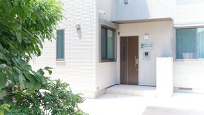 A building with a white brick exterior, a door with a sign, and a small step leading to the entrance.