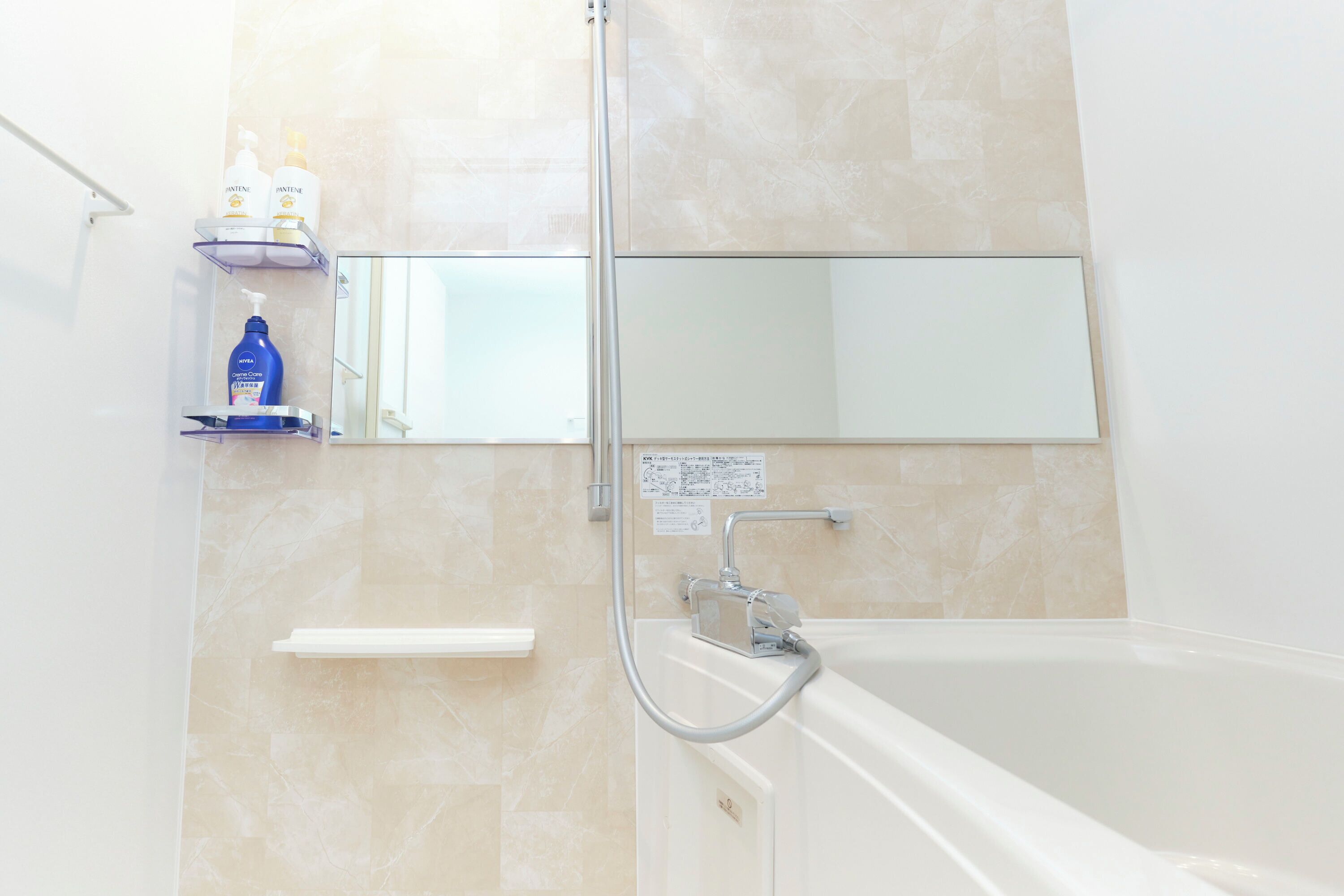 A bathroom with a bathtub, a shower, and a mirror.