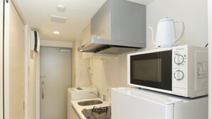 A compact kitchen with a microwave, stove, and a small sink.