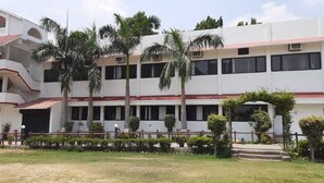 A multi-story building with a white facade and red accents, featuring balconies and a central entrance. - Avexia Funcity Resort (Mirzapur)