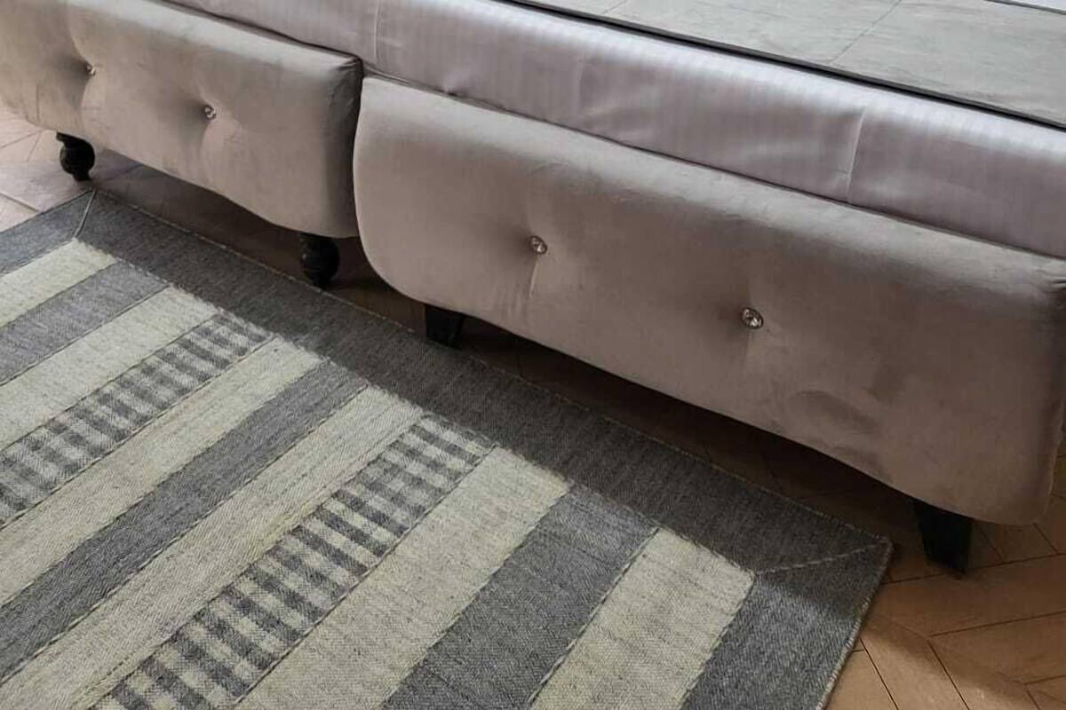 Una camera da letto ordinata con un letto grande, una panca di legno e uno specchio a parete.