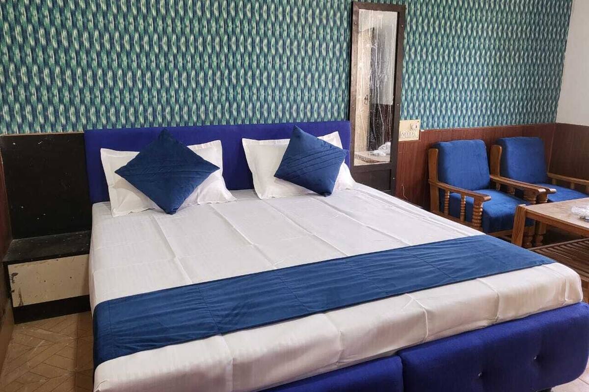 Una camera d'albergo con un letto grande, biancheria azzurra e bianca, una testiera in legno e un muro decorato.