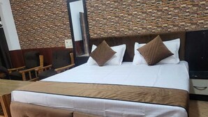 A bed with a wooden headboard, white bedding, and brown pillows. - Avexia Funcity Resort (Mirzapur)