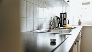 Una cocina moderna con un lavamanos de acero inoxidable, una cafetera y una planta en maceta.