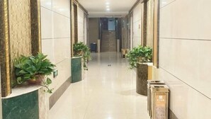 A hallway with marble walls, potted plants, and a staircase in the distance. - Long Yin Tang Hotel (Xingyang)