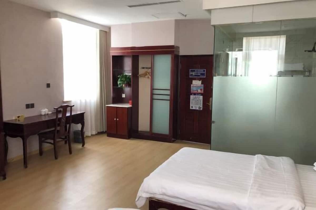 Una habitación de hotel con cama, escritorio, armario y espejo.