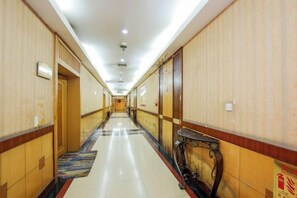 Un pasillo de hotel con puertas a ambos lados, suelo de baldosas y una zona alfombrada.