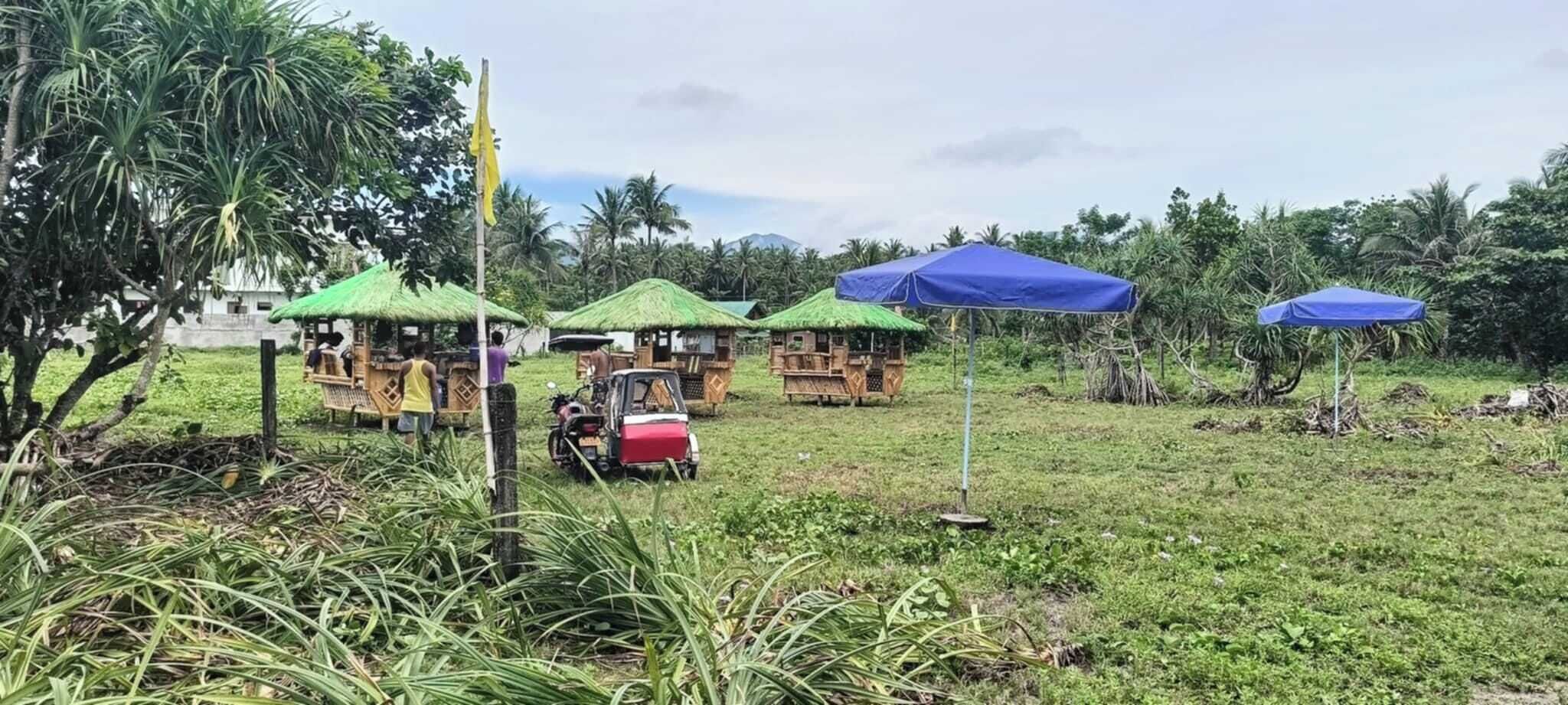 Un paisaje rural con chozas de techo de paja y un dosel azul.