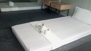 A minimalist hotel room with a single bed, a small desk, and a chair. - The Waves at Socorro Baler- Hotel A (Baler)