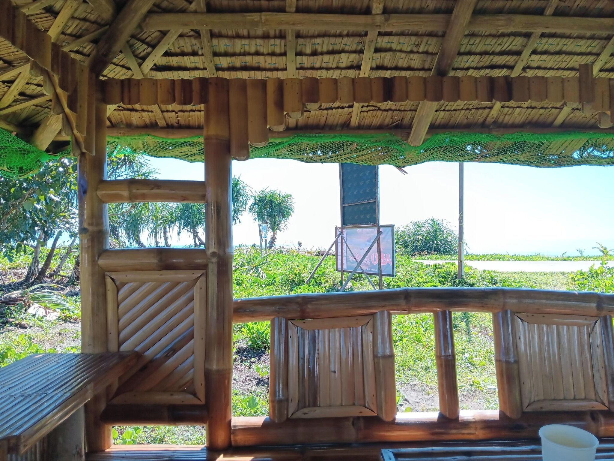 A wooden structure with a thatched roof, featuring a bench and a table.