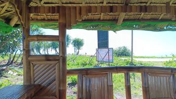 A wooden structure with a thatched roof, featuring a bench and a table.