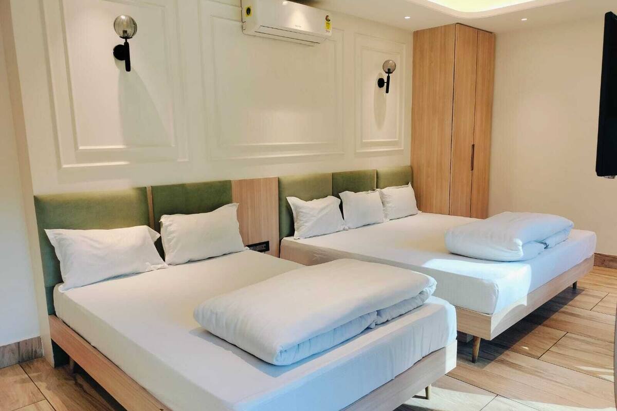 Habitación de hotel con dos camas, un armario y un equipo de aire acondicionado.