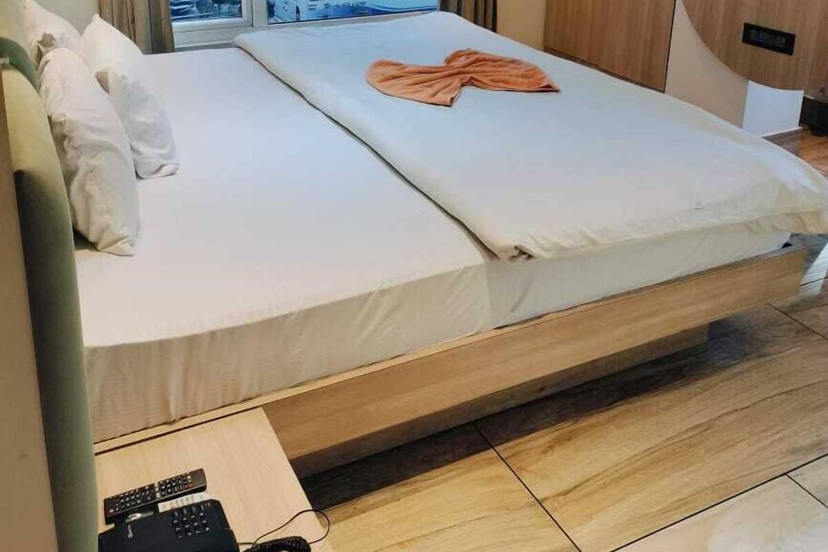 Habitación de hotel moderna con una cama grande, un televisor montado en la pared y vistas a un autobús en la ventana.