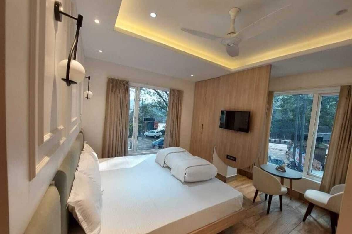 Una habitación de hotel moderna con una cama grande, un escritorio y un televisor.