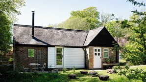 A rustic house with a brick exterior, a white door, and a chimney. - Hop at Tipsy Cottages: a romantic rural retreat (Robertsbridge)