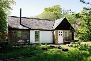 A rustic house with a brick exterior, a white door, and a chimney.