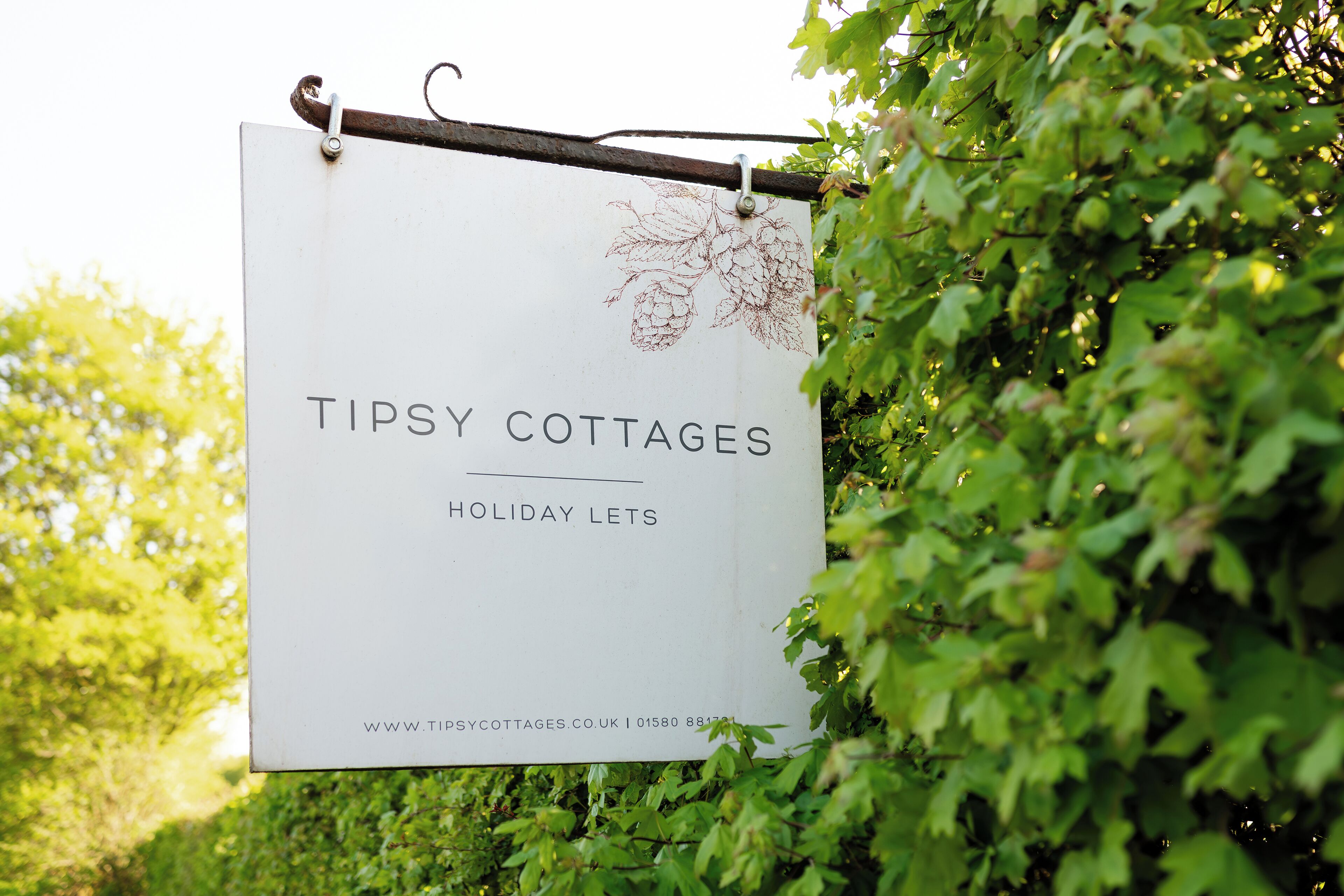 A sign for Tipsy Cottages holiday lets with a website URL and phone number.