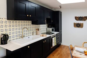 A kitchen with black cabinets, a white countertop, a microwave, and a coffee maker.