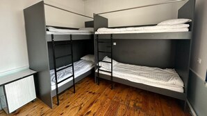 A room with three bunk beds, a small desk, and a radiator. - Sunny Hostel (Osh)