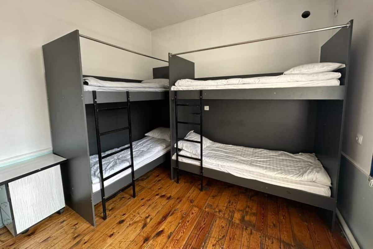 Una habitación con tres literas, un escritorio pequeño y un radiador.