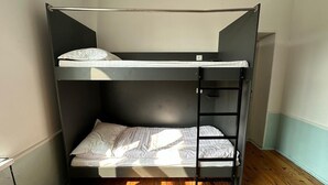 A bunk bed with a ladder, a white mattress, and a wooden floor. - Sunny Hostel (Osh)