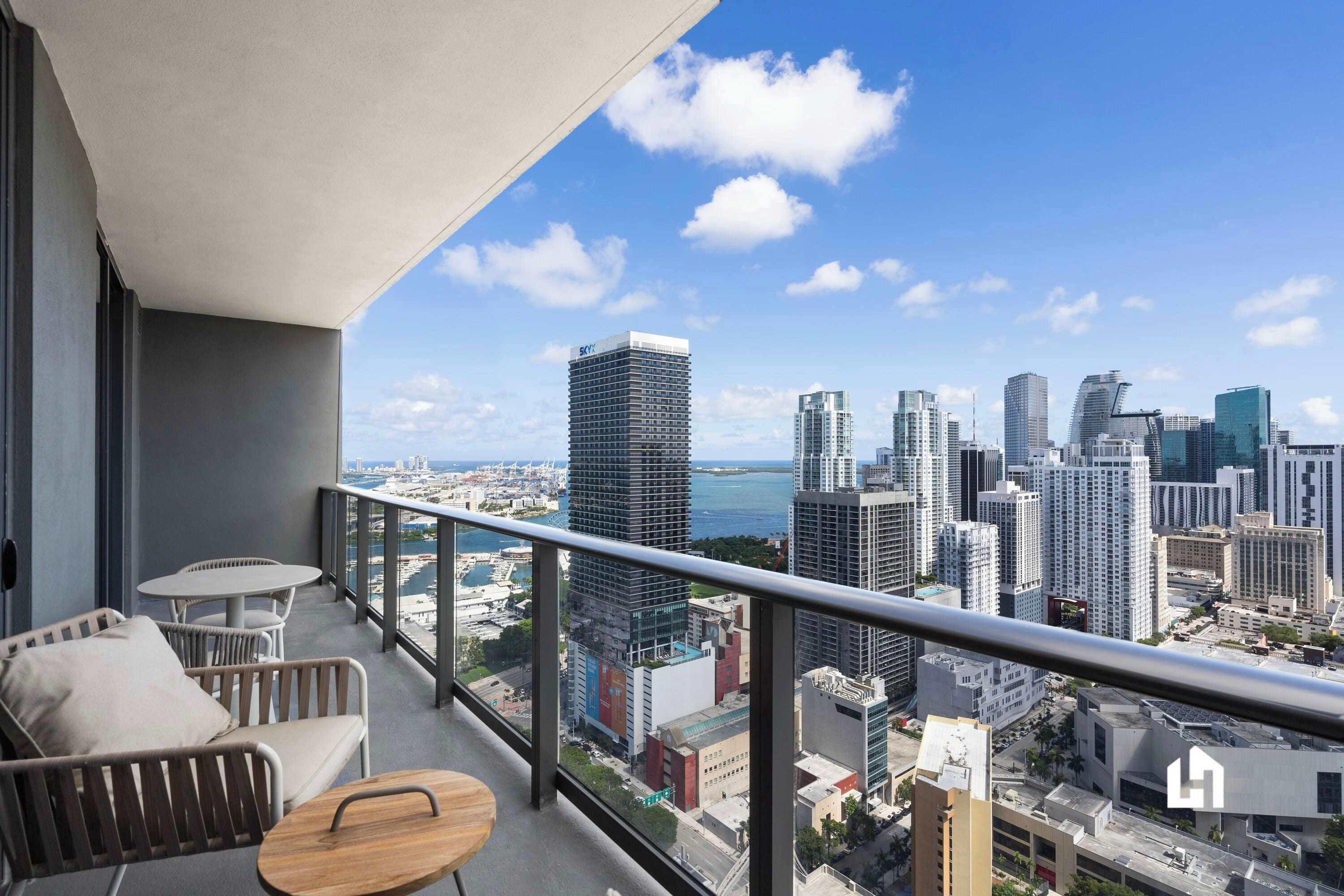 A balcony with a city view, a sofa, a small round table, and a railing.