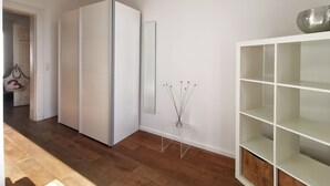 A modern room with a white wardrobe, a mirror, and a white shelving unit. - Vacation apartment Schuppen XIII with spacious terrace  (Norderney)