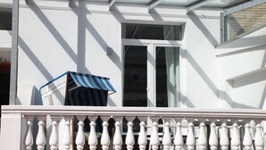 A white building with a balcony featuring a white balustrade. - Vacation apartment Schuppen XIII with spacious terrace  (Norderney)