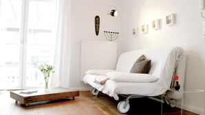 A modern living room with a white sofa, a small table, and a radiator. - Vacation apartment Schuppen XIII with spacious terrace  (Norderney)