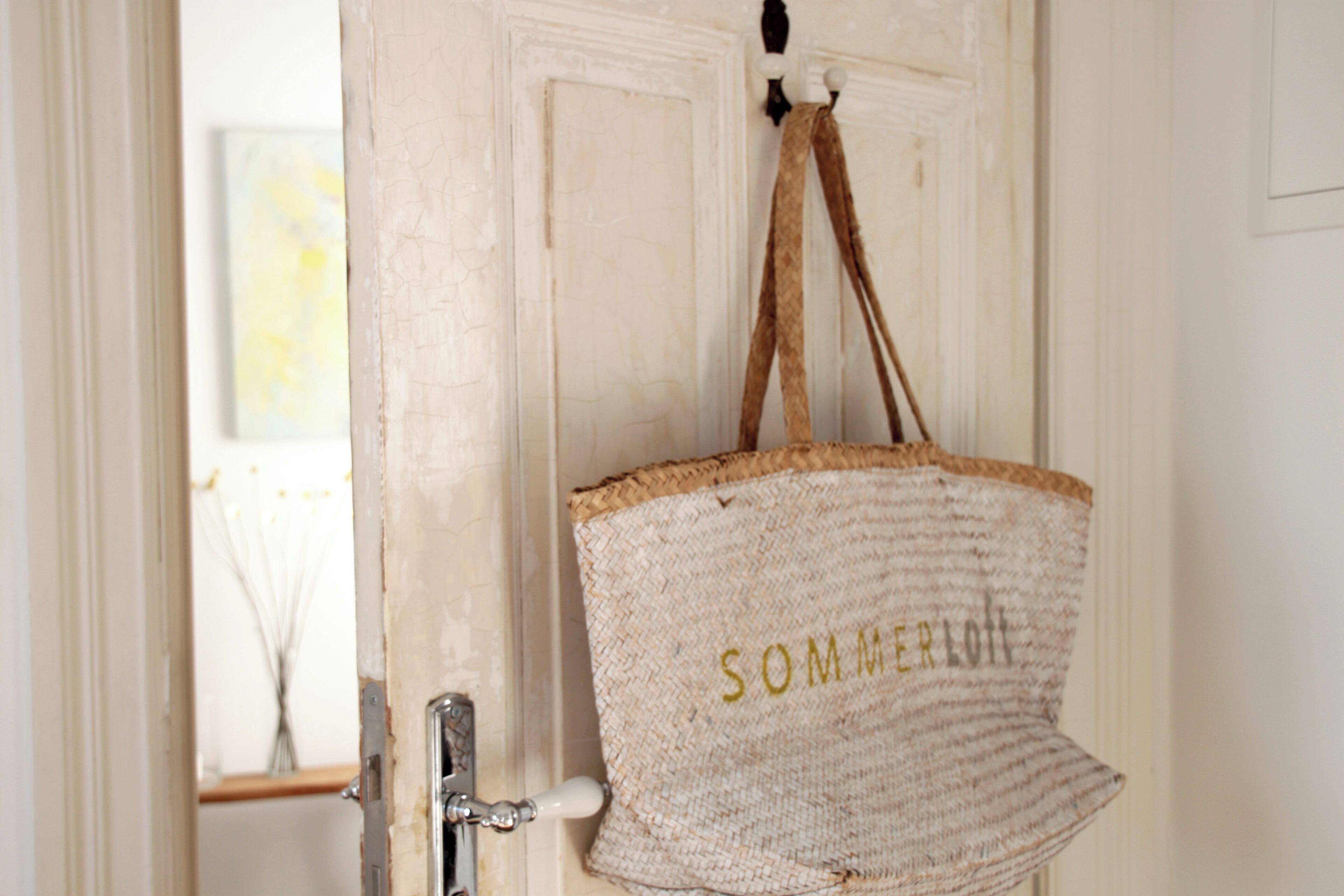 A door with a woven bag hanging on a hook, labeled "SOMMERLOTT".