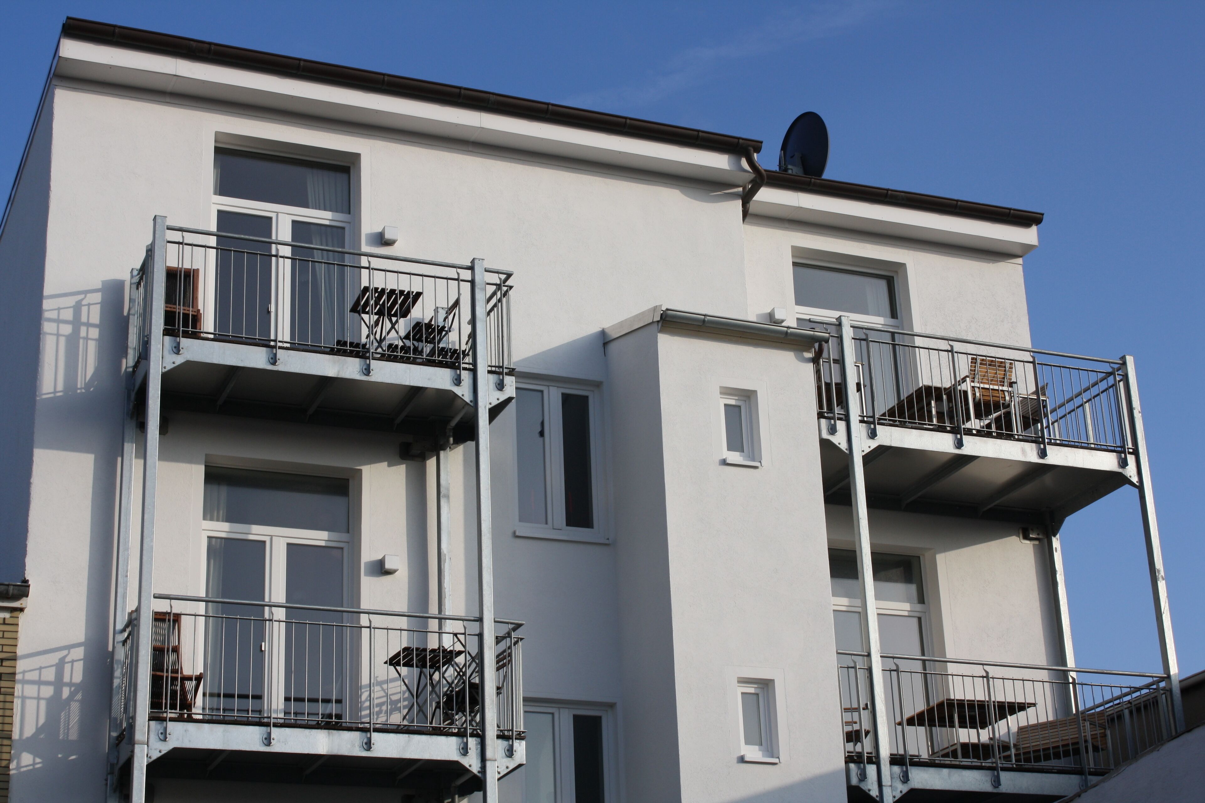 Un immeuble résidentiel à plusieurs étages, doté de balcons, de fenêtres et d’une antenne parabolique.