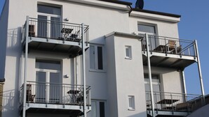 Een meerlaags woongebouw met balkons, ramen en een schotelantenne.