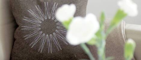 A pillow with a sunburst design on a beige sofa.