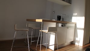 Een moderne keuken met een houten aanrecht, twee barstoelen, een vaatwasser en een koffiemachine.